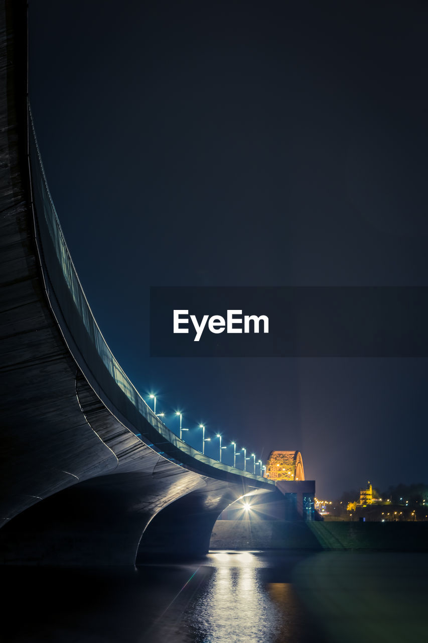 Illuminated bridge over road in city at night