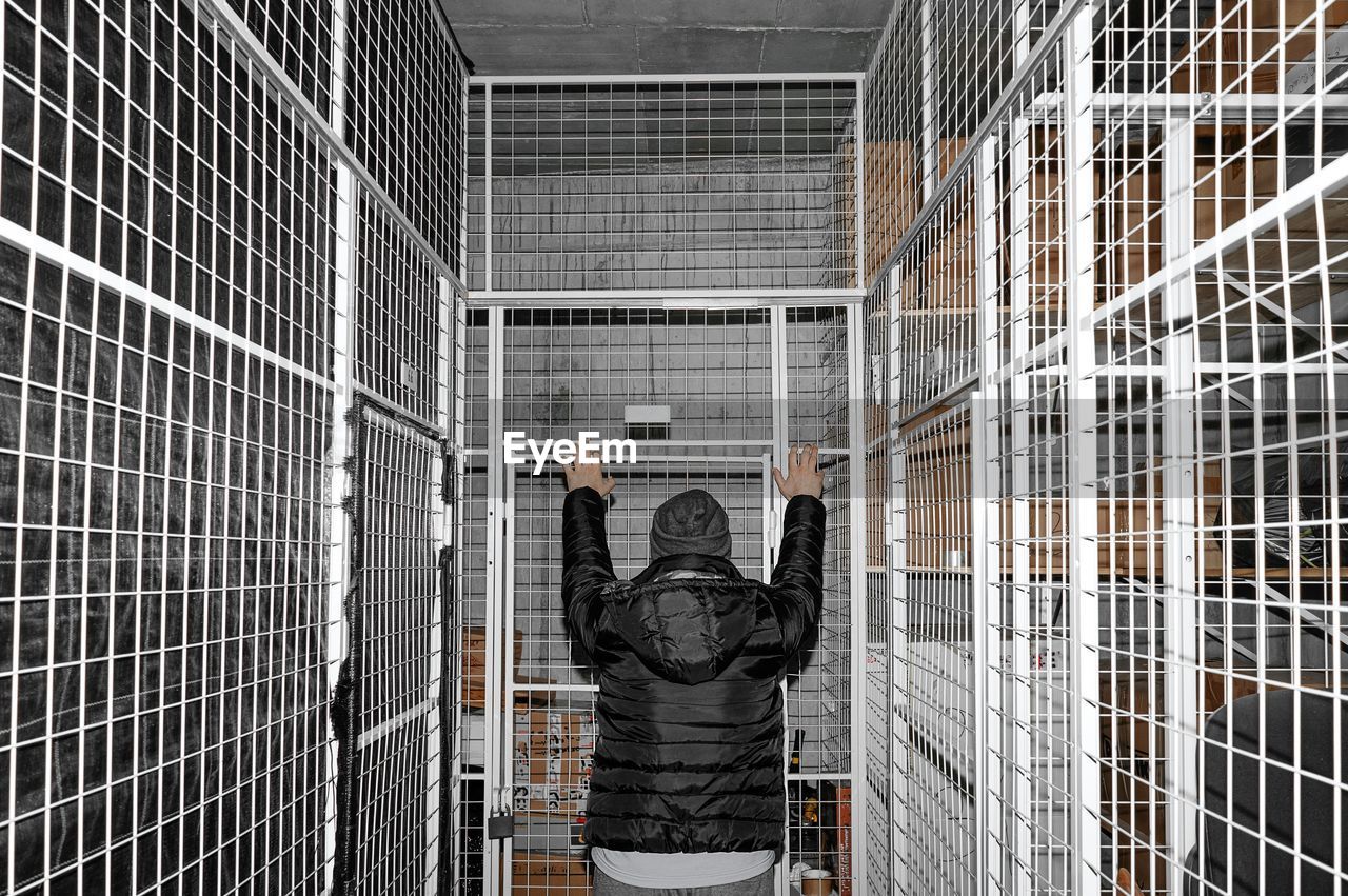 Rear view of a man standing against fence in room