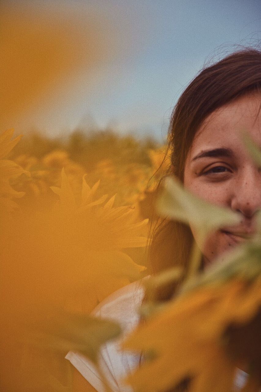 CLOSE-UP OF BEAUTIFUL YOUNG WOMAN AGAINST SKY