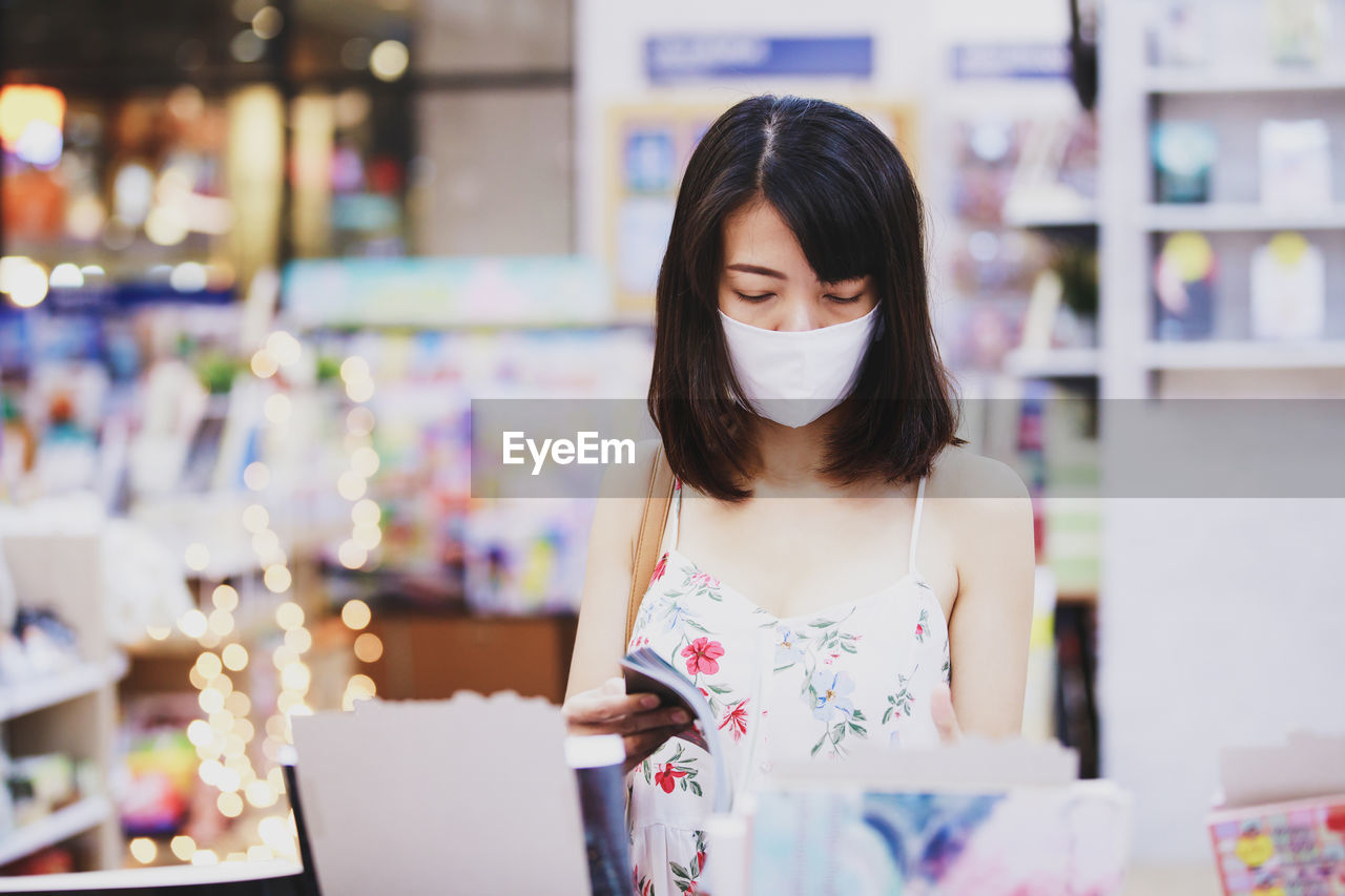 WOMAN LOOKING AT CAMERA WHILE STANDING ON LAPTOP IN CITY