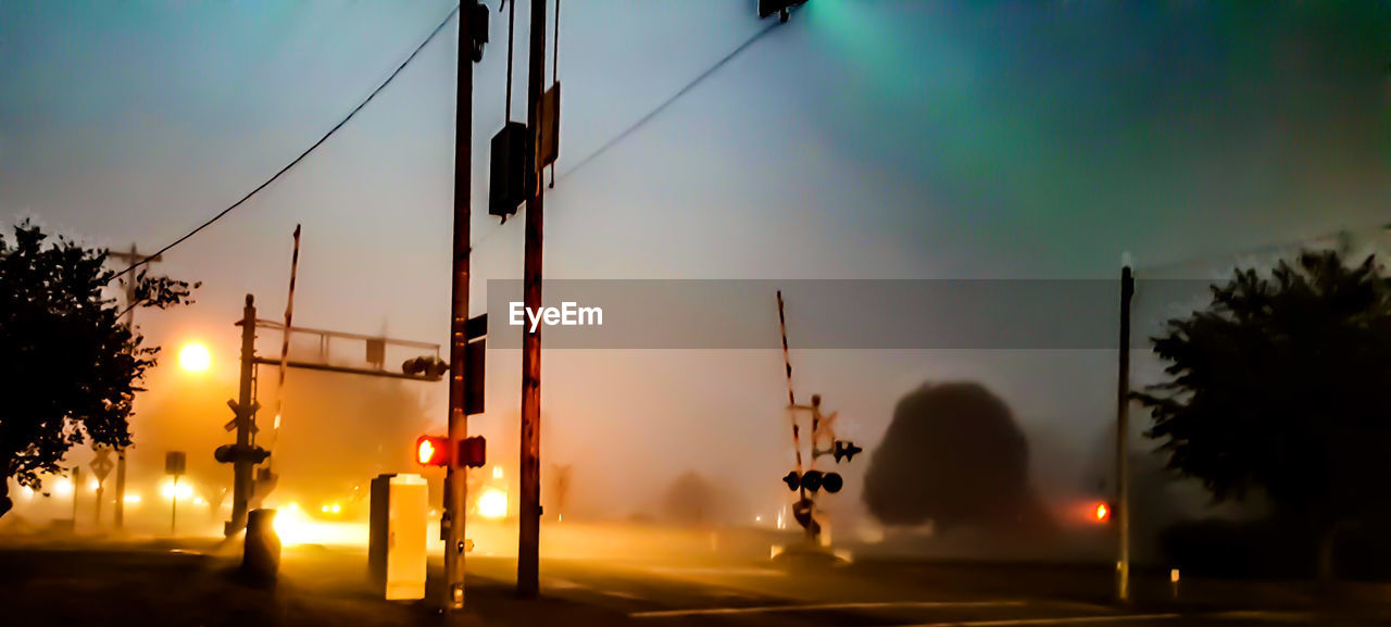 LOW ANGLE VIEW OF ILLUMINATED STREET LIGHTS AGAINST SKY