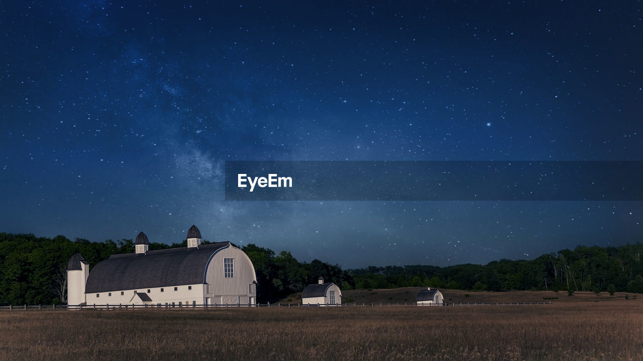 Three white barns in a far away farm land at night with stars