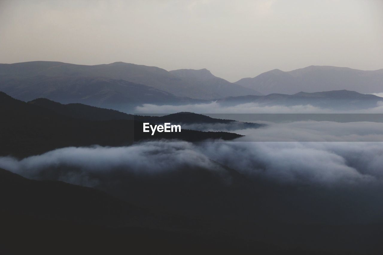 Scenic view of clouds covered mountains at dusk