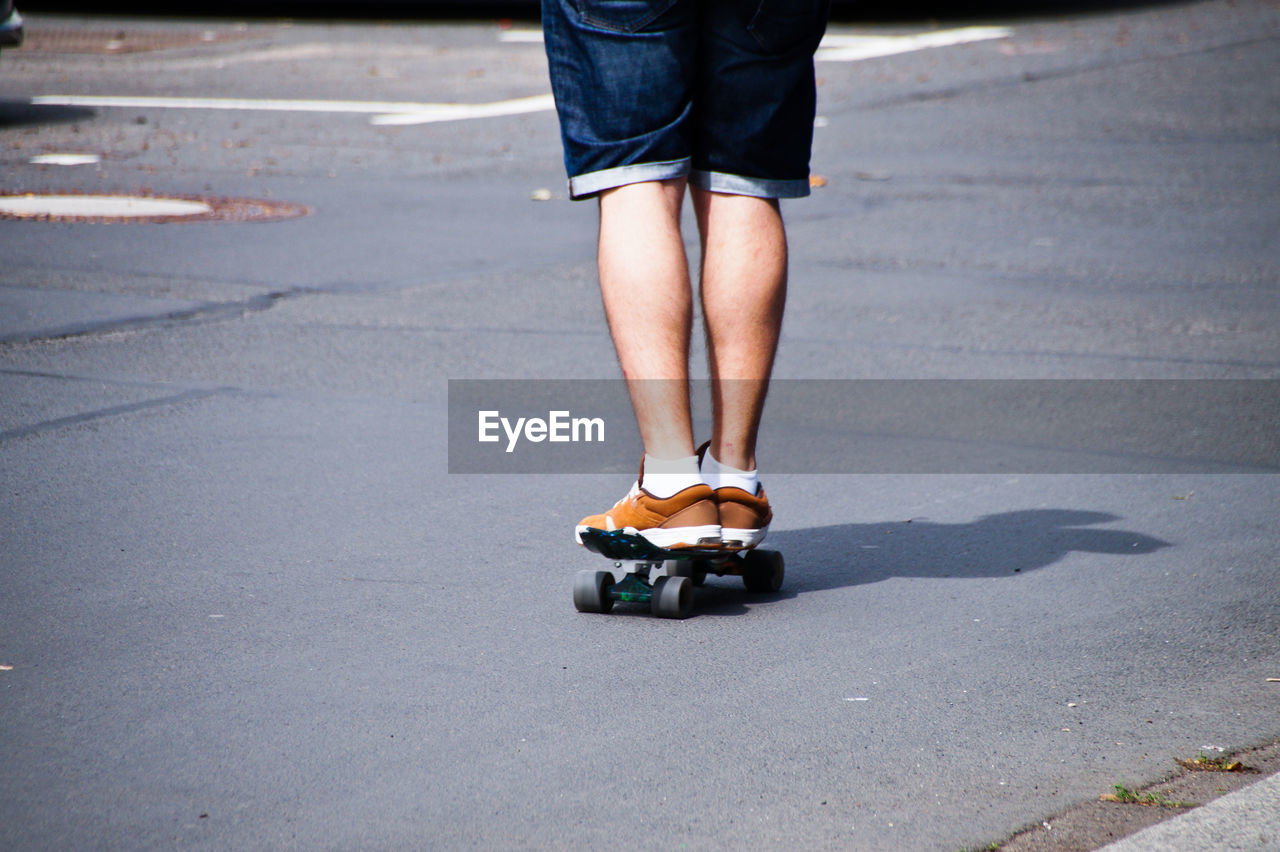 Low section of man skateboarding on road