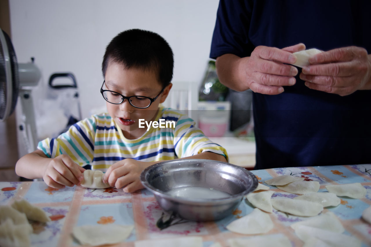 Boy preparing food by father on kitchen