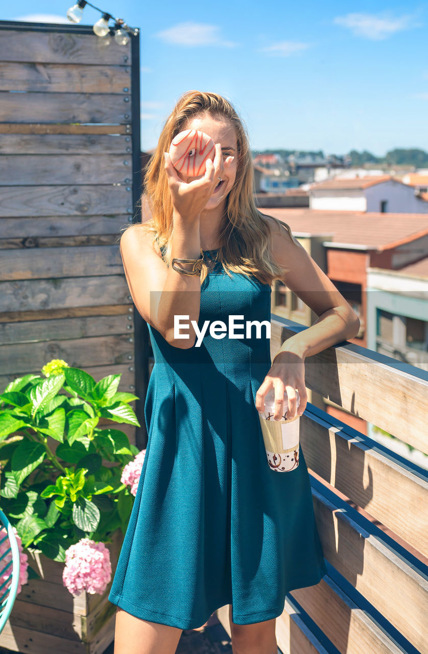 Funny unrecognizable woman posing covering her face with a donut