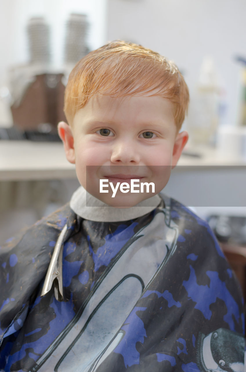 Little red-haired boy in the barbershop looks at the camera. boy 4 years old in a hairdresser