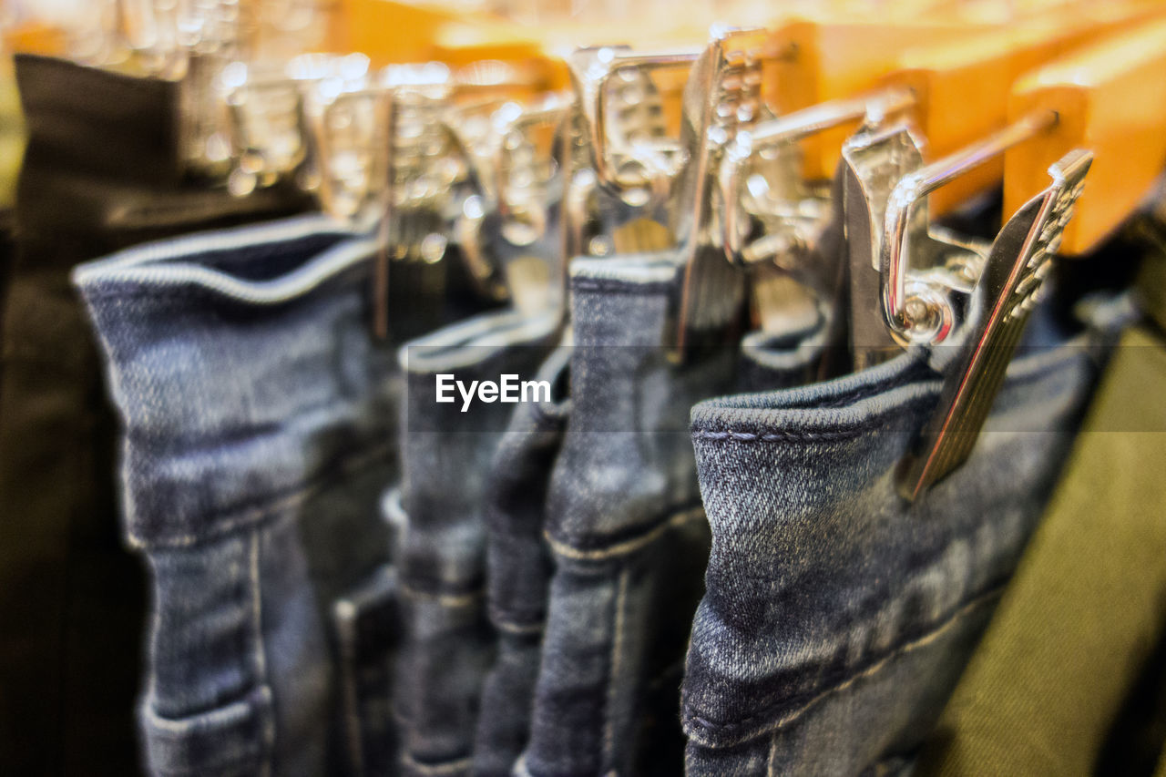 Close-up of jeans hanging from coathangers at store
