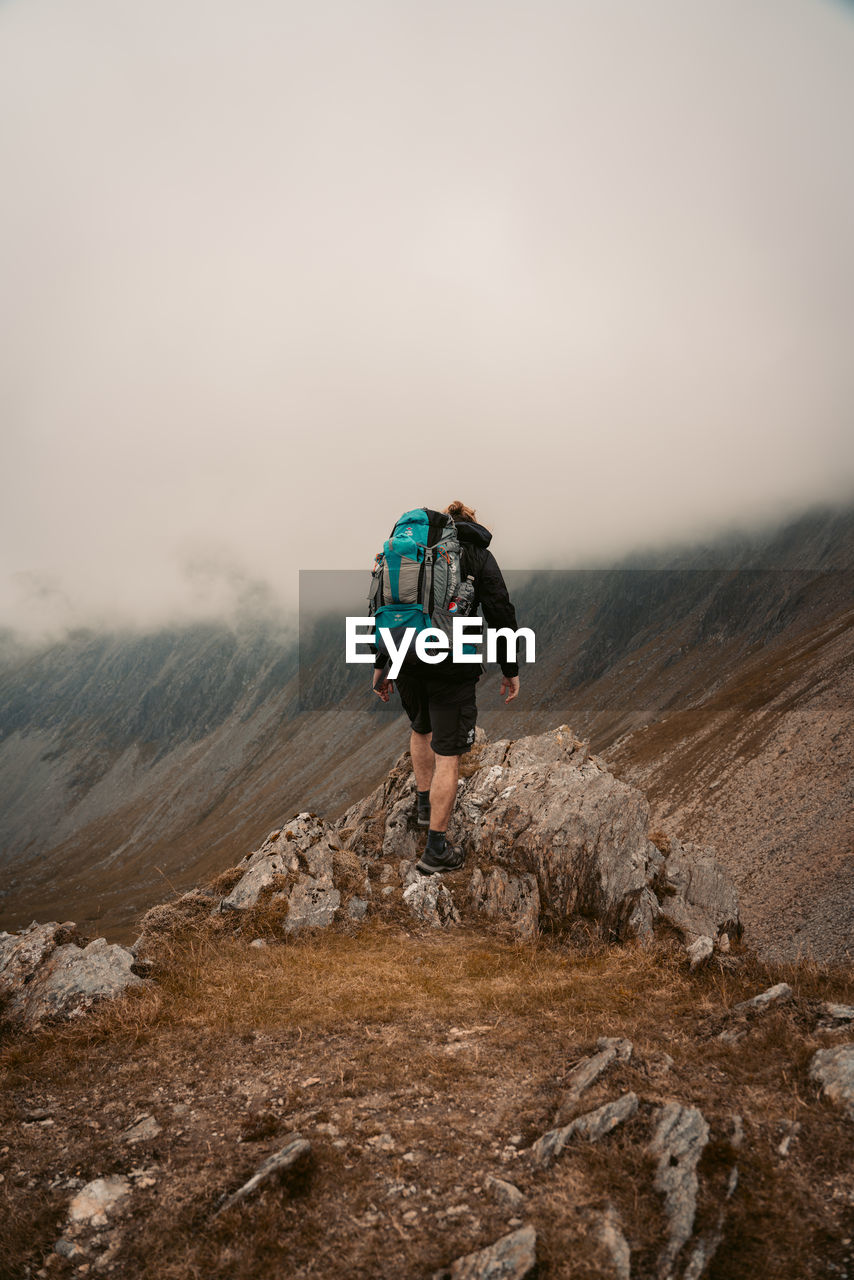 Rear view of man on mountain against sky