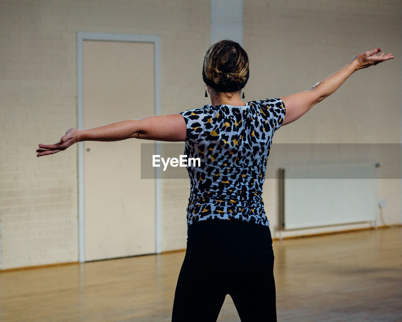 Woman with arms outstretched dancing on hardwood floor at studio