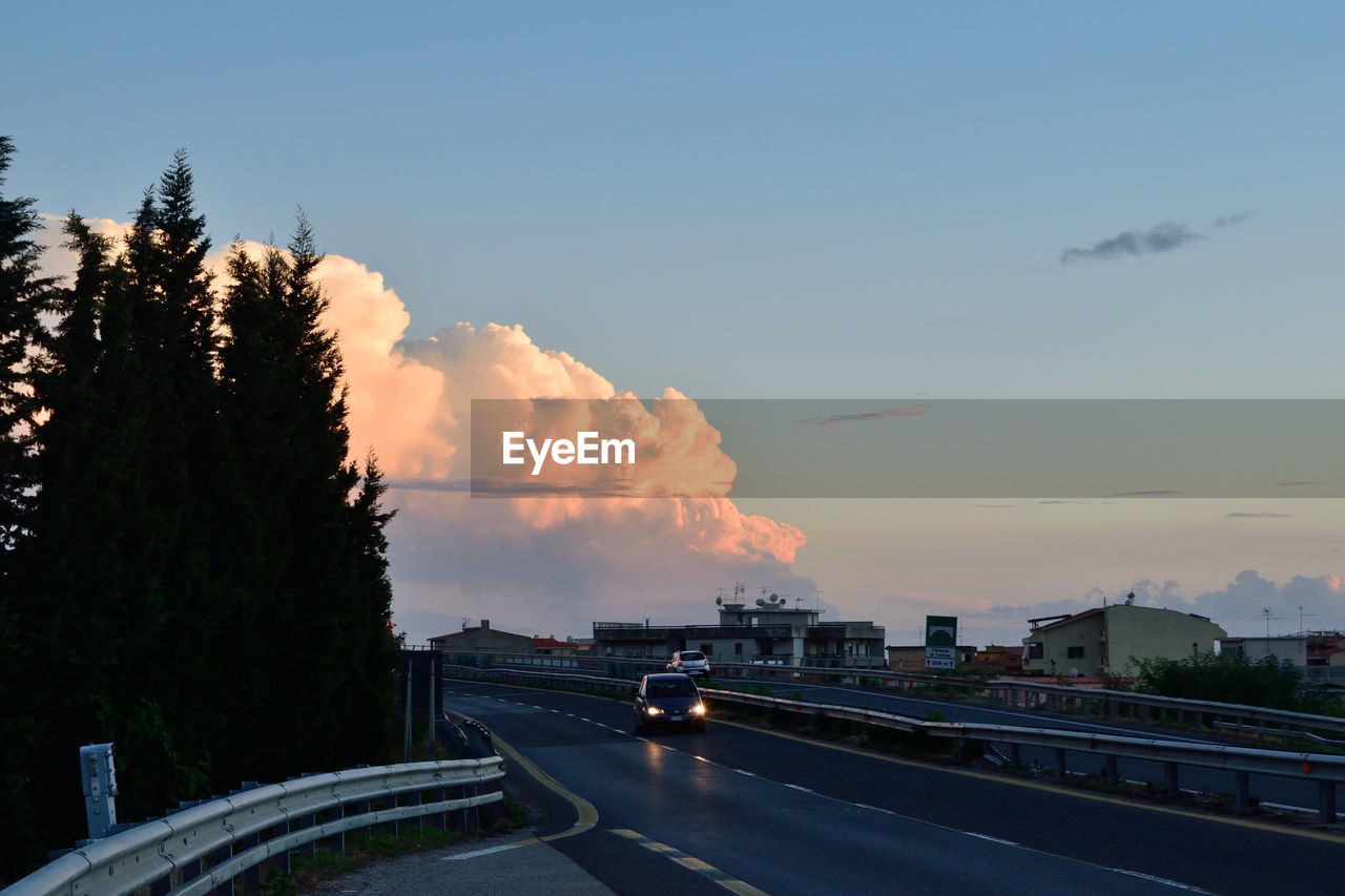 Cars on road against cloudy sky