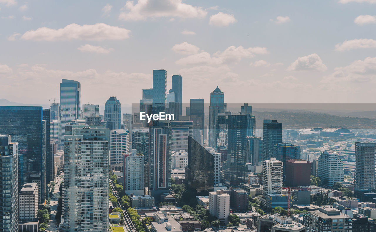 Aerial view of city buildings against cloudy sky