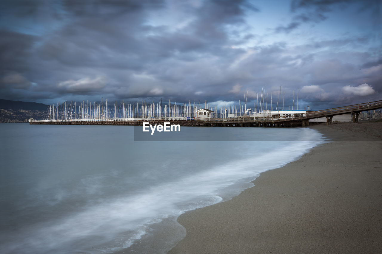 VIEW OF COMMERCIAL DOCK AGAINST CLOUDY SKY