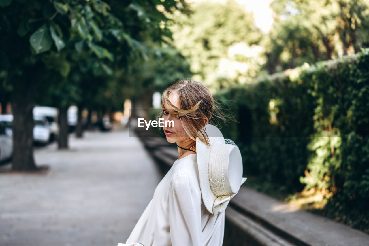 Side view portrait of woman standing on footpath