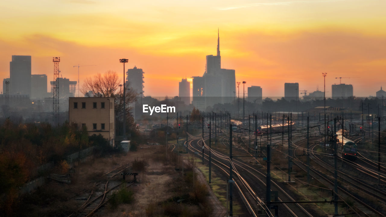 HIGH ANGLE VIEW OF RAILROAD TRACKS AMIDST BUILDINGS IN CITY