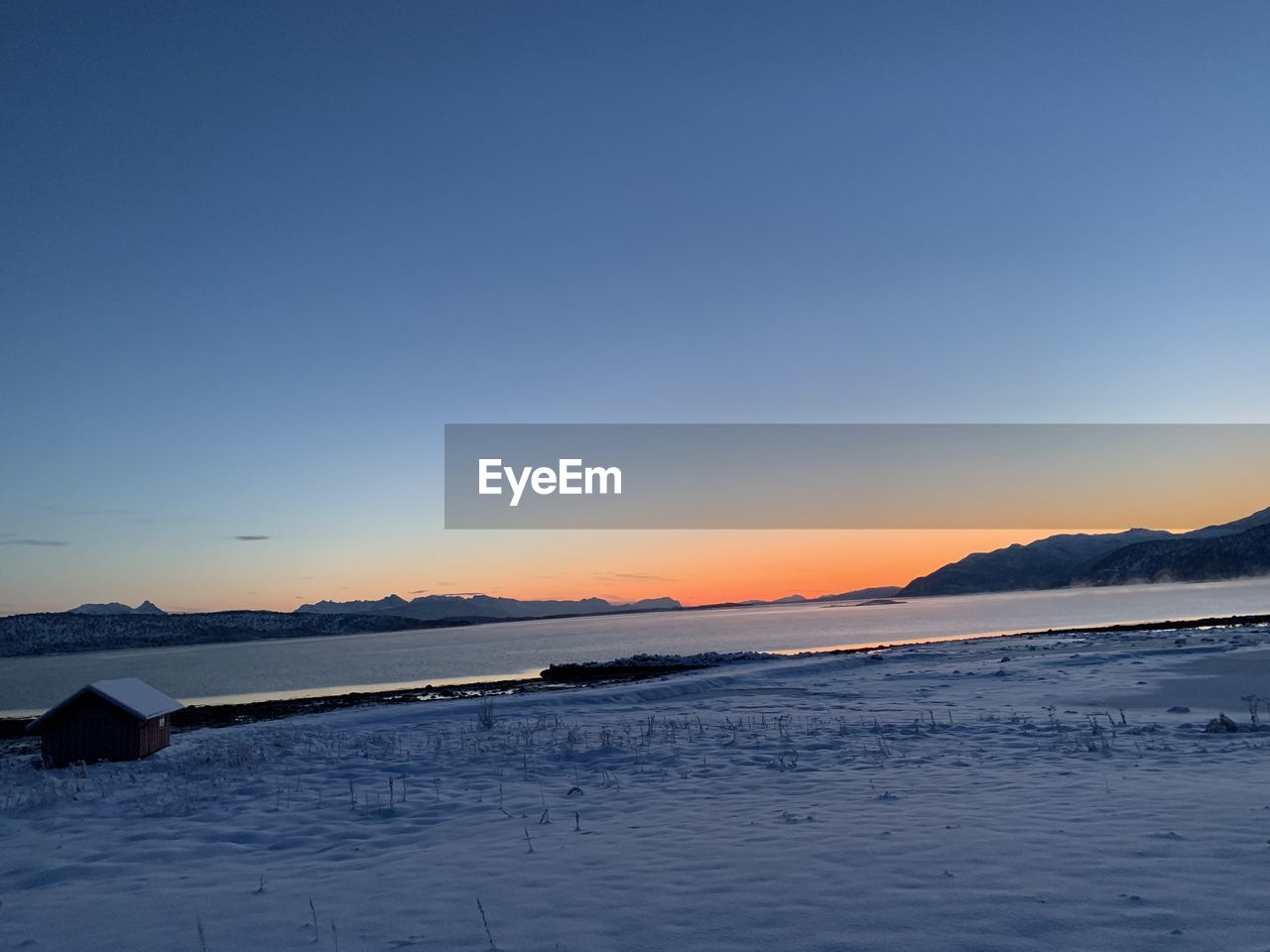 SCENIC VIEW OF FROZEN LAKE AGAINST SKY AT SUNSET