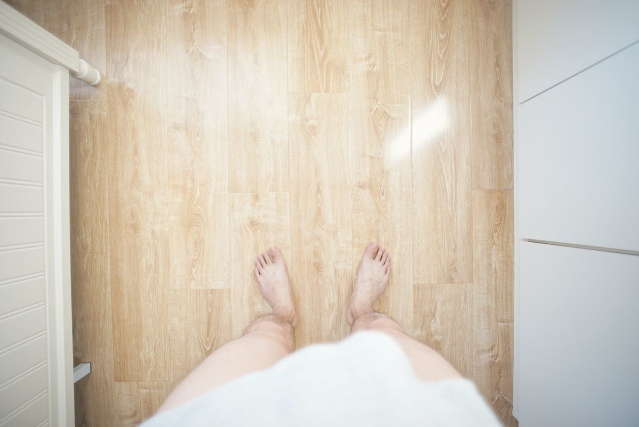 Low section of man standing on floorboard