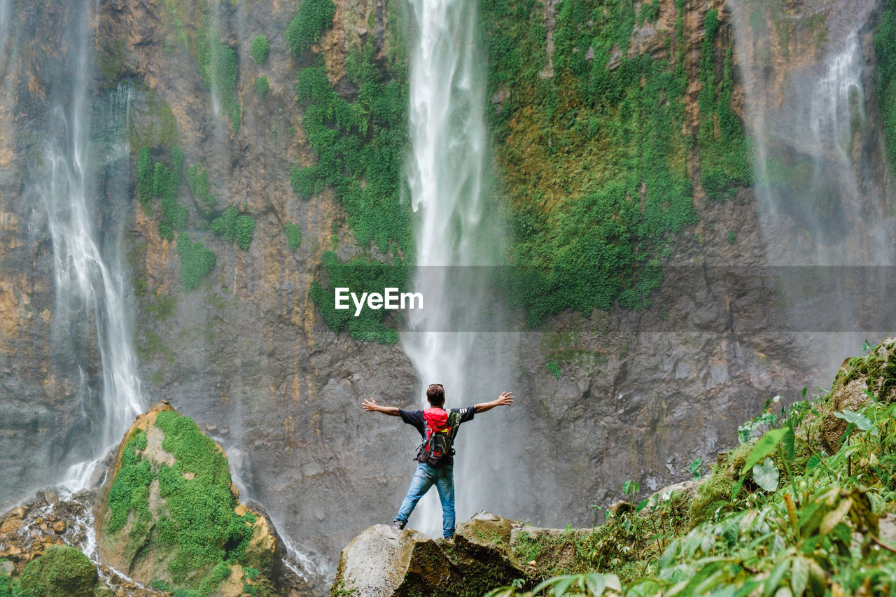 SCENIC VIEW OF WATERFALL AGAINST MOUNTAIN