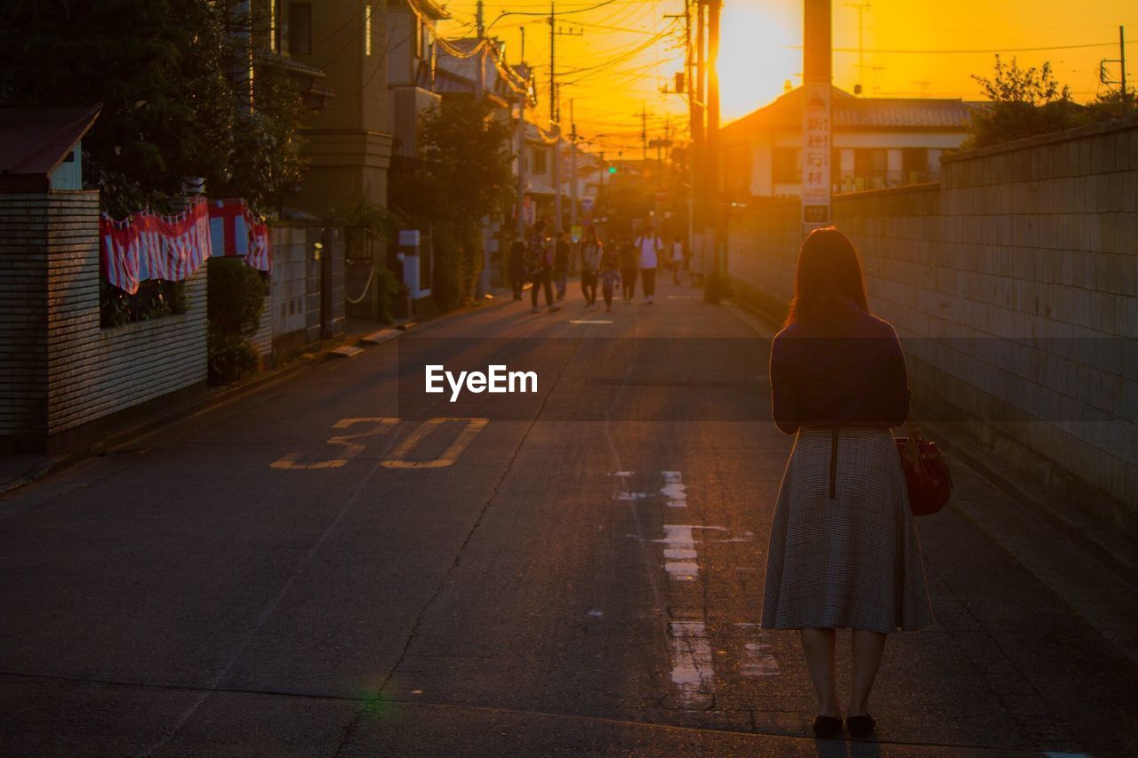 Woman walking on road at sunset