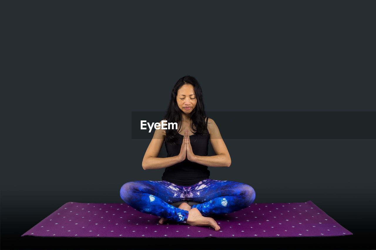 YOUNG WOMAN SITTING ON BLACK BACKGROUND