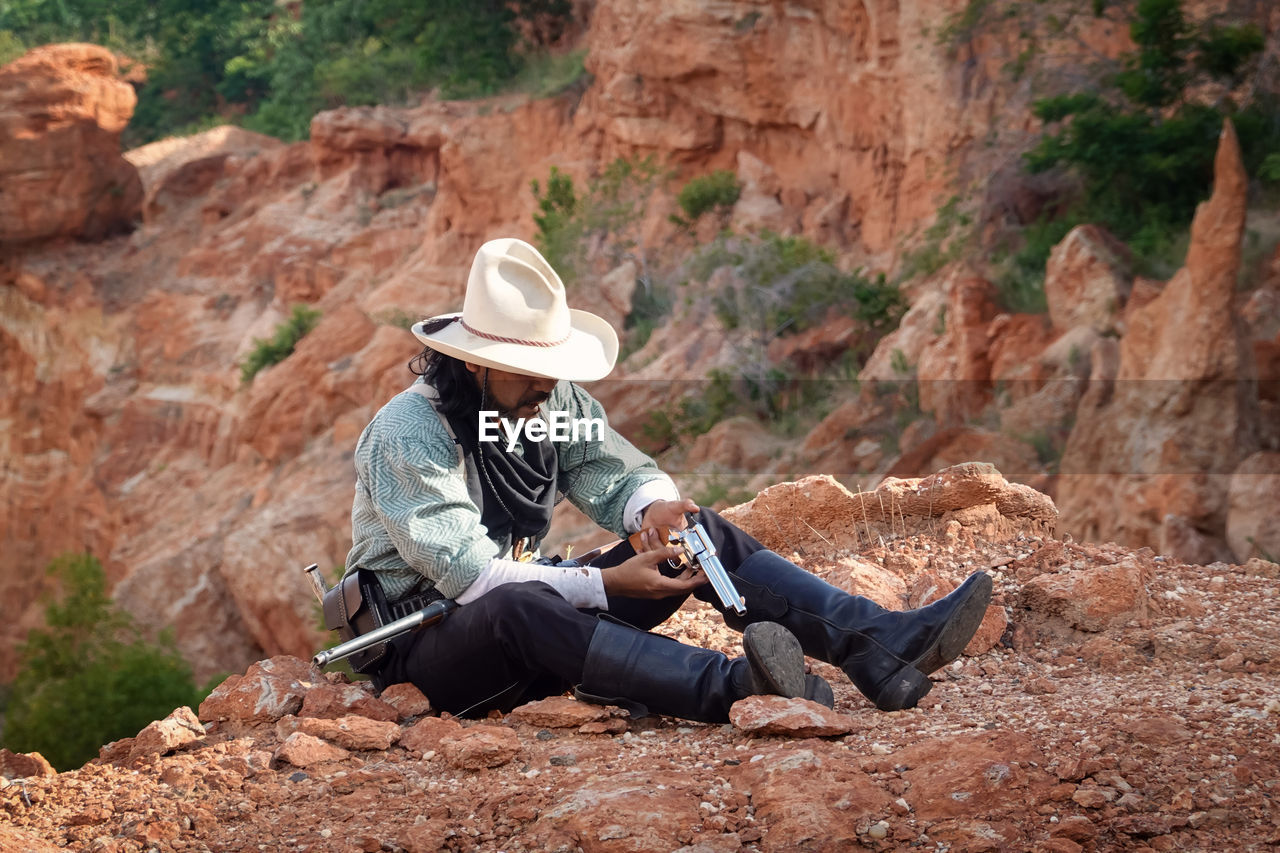 A cowboy man sitting and resting to smoke to relax