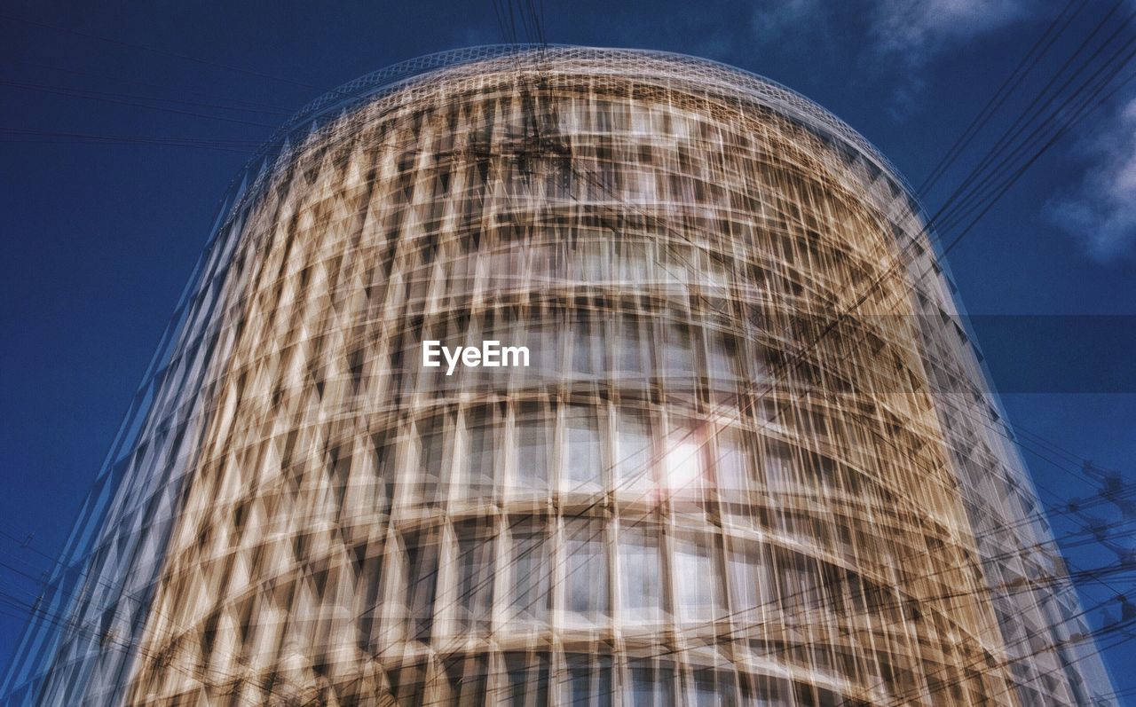 LOW ANGLE VIEW OF MODERN GLASS BUILDING AGAINST SKY