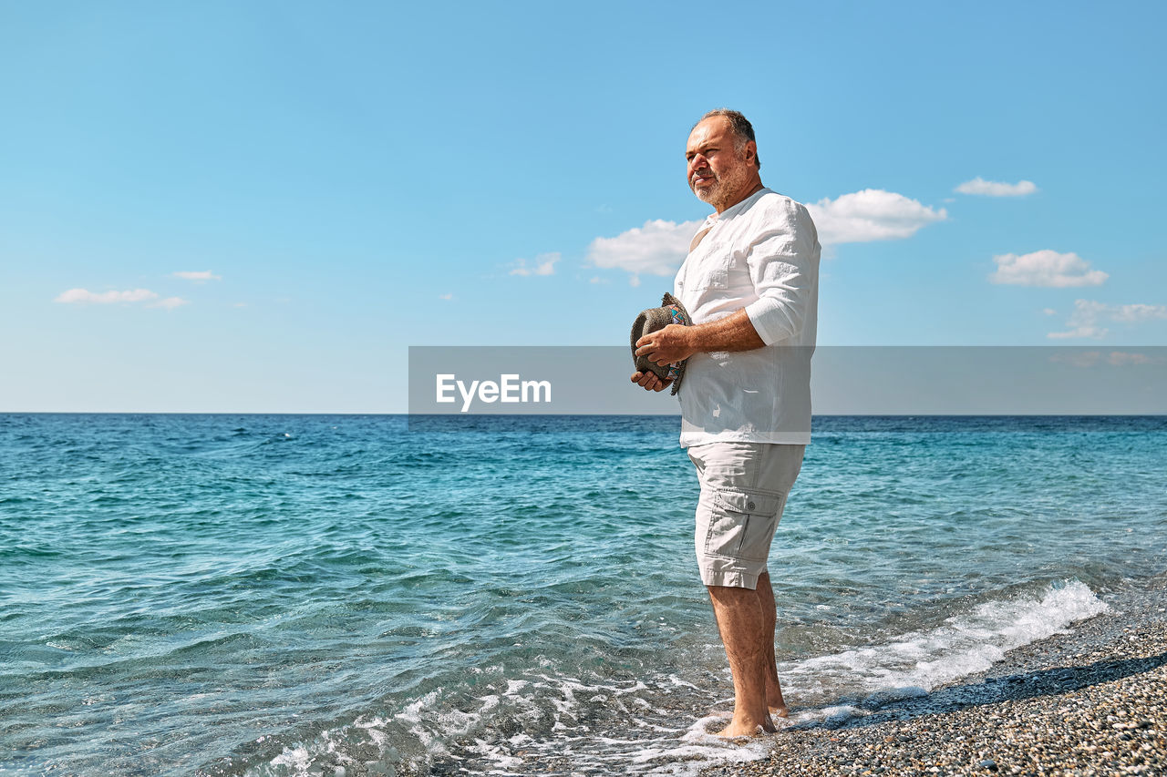 Happy middle-aged bearded man walking along beach. concept of leisure activities, wellness, freedom