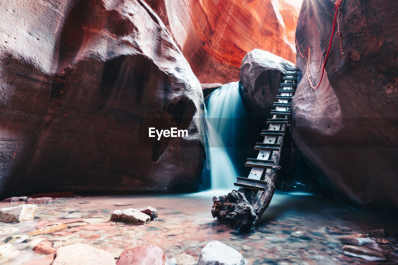 Long exposure of waterfall flowing over rock step in slot canyon