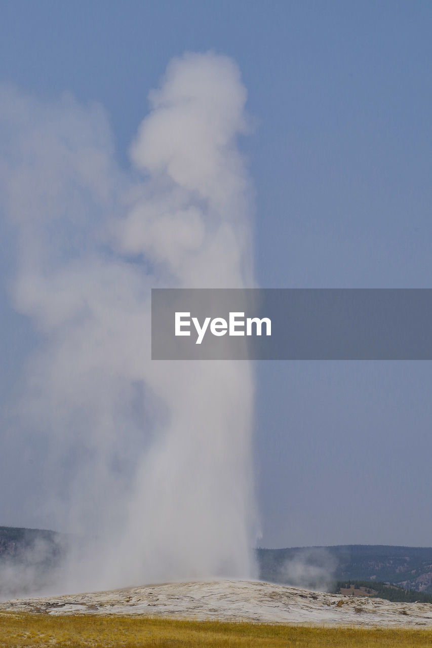 Steam emitting from volcanic landscape against clear sky