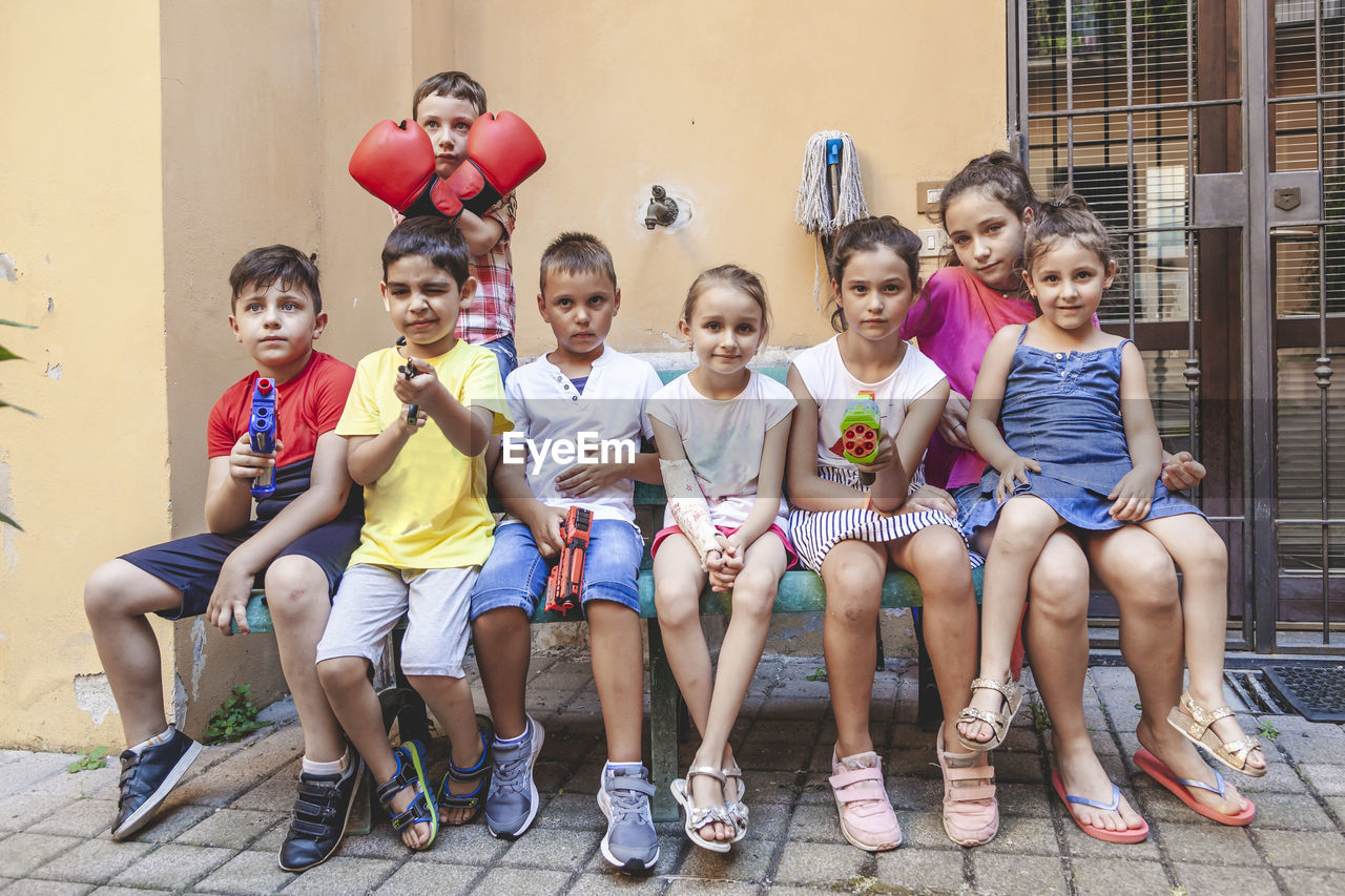 Group of little boys of different ages sitting having fun and playing together in a courtyard