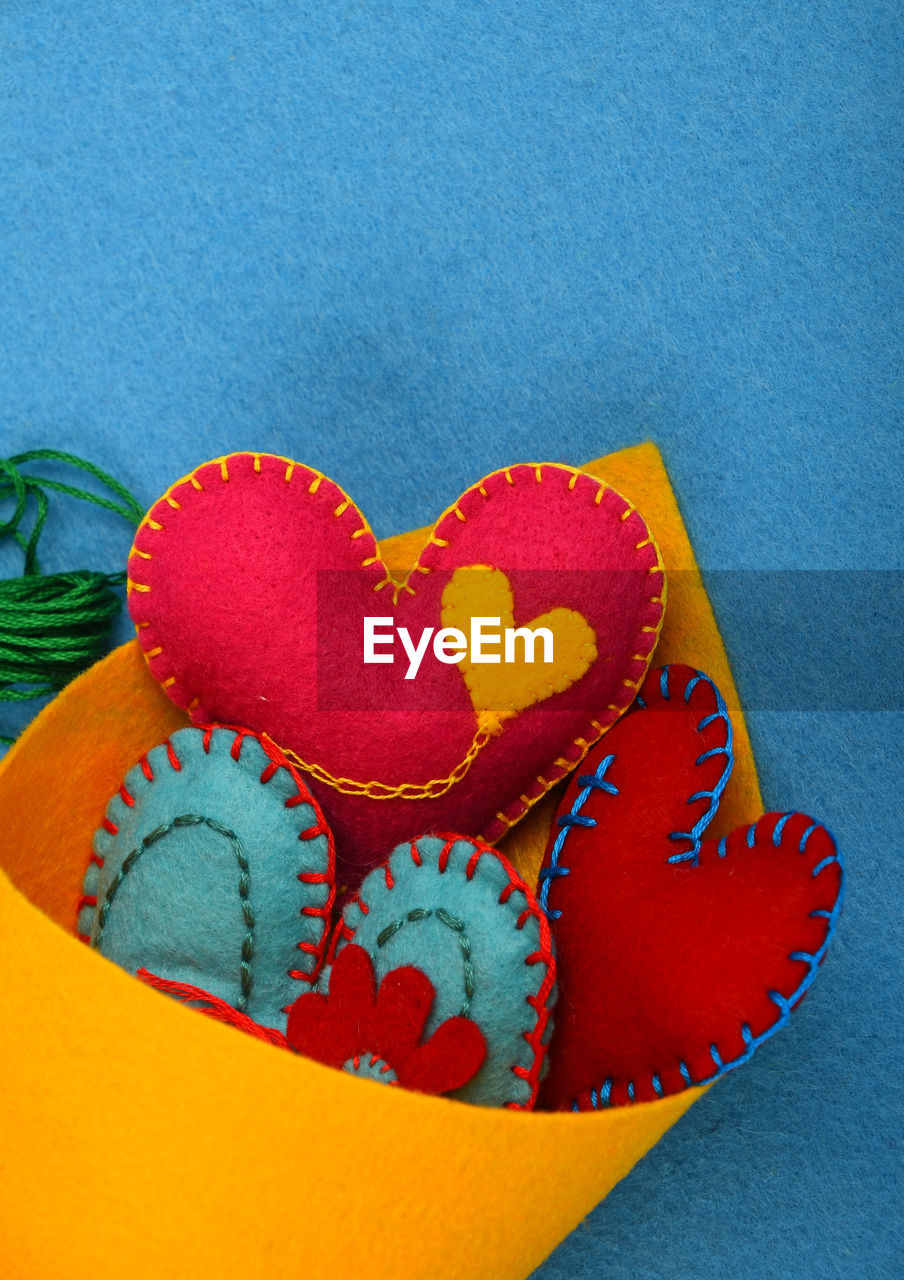 Close-up of heart shape decorations in yellow fabric against blue floor