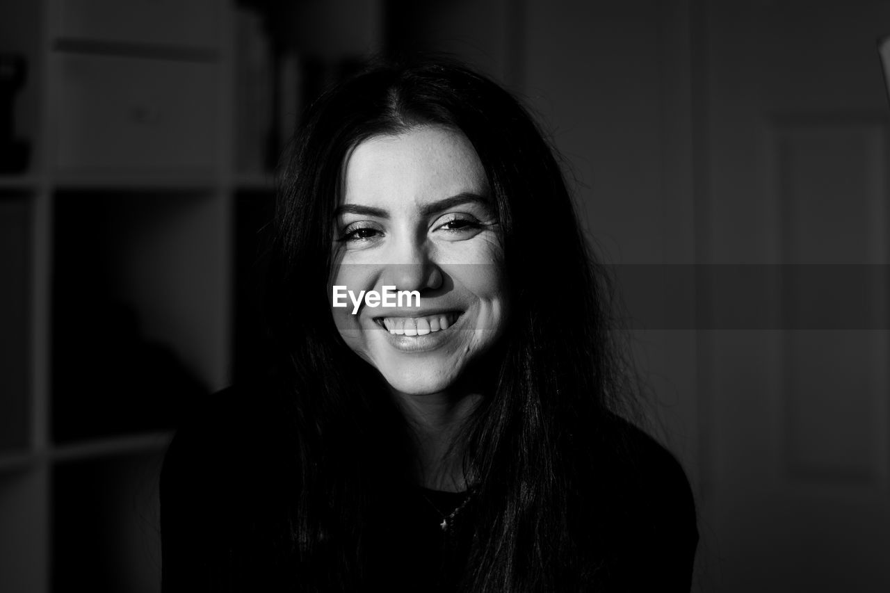 Portrait of smiling young woman standing at home