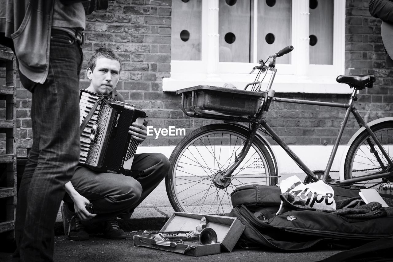 PEOPLE SITTING ON BICYCLE AGAINST WALL