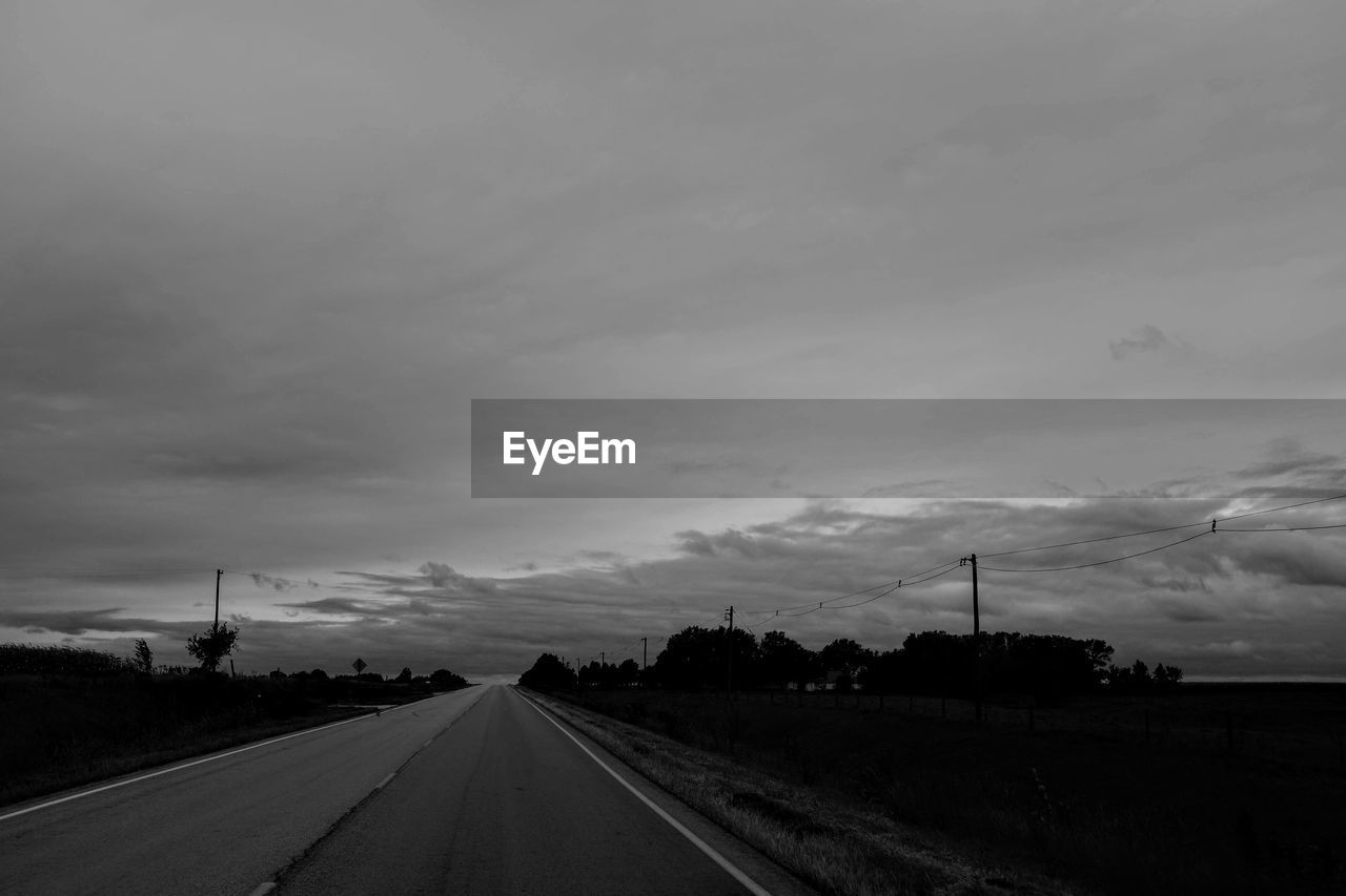 Road amidst field against sky at dusk