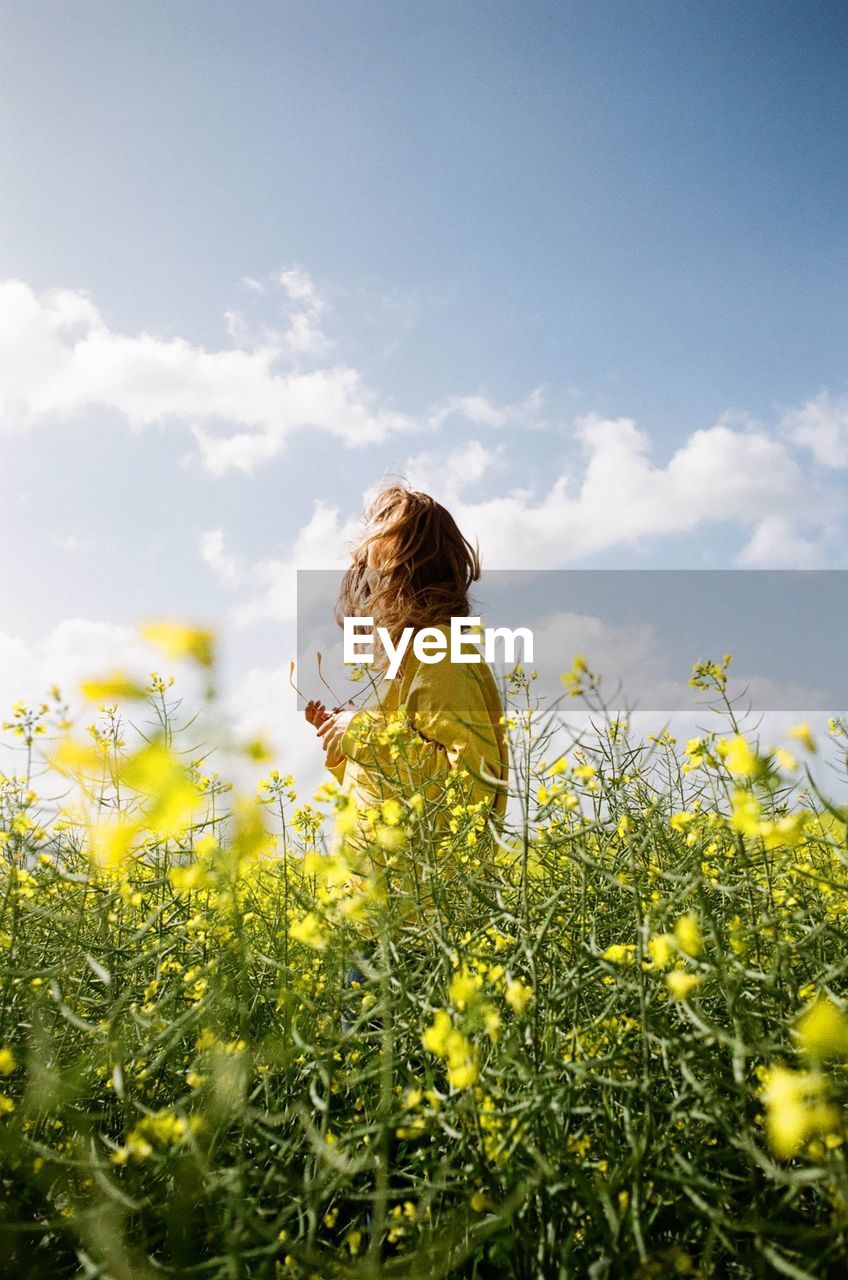 Low angle view of woman standing on field against sky