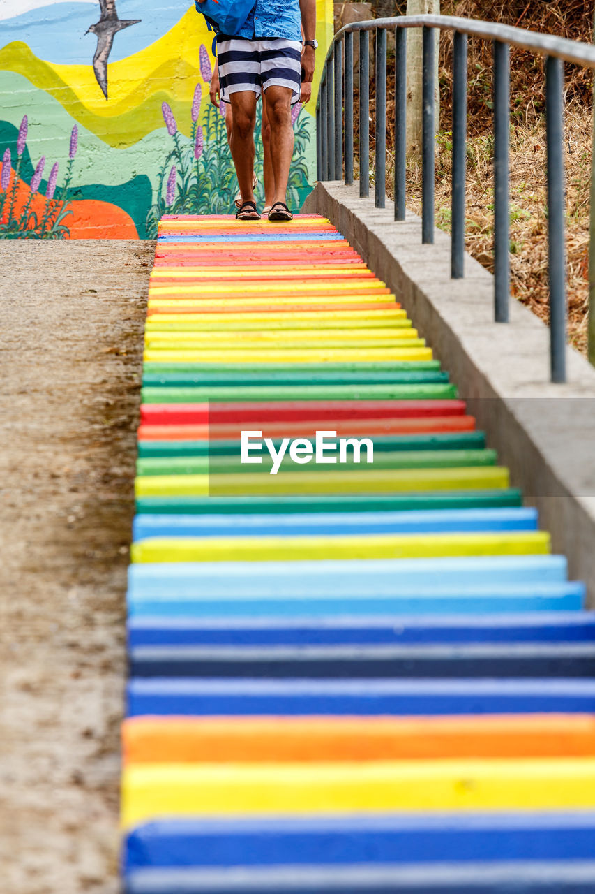 LOW SECTION OF MEN STANDING ON MULTI COLORED UMBRELLA