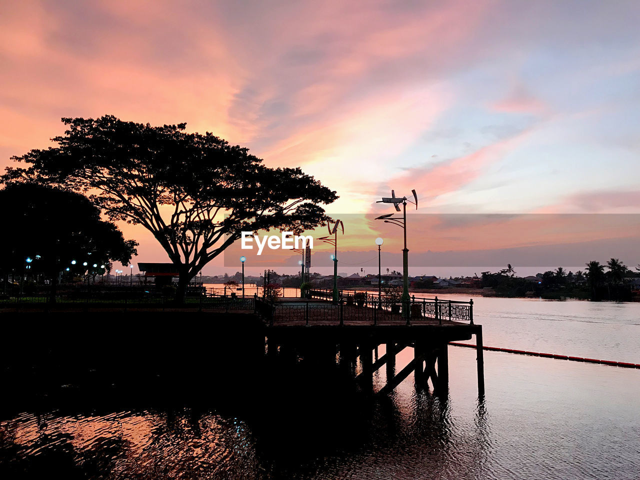 SILHOUETTE TREES BY LAKE AGAINST ORANGE SKY