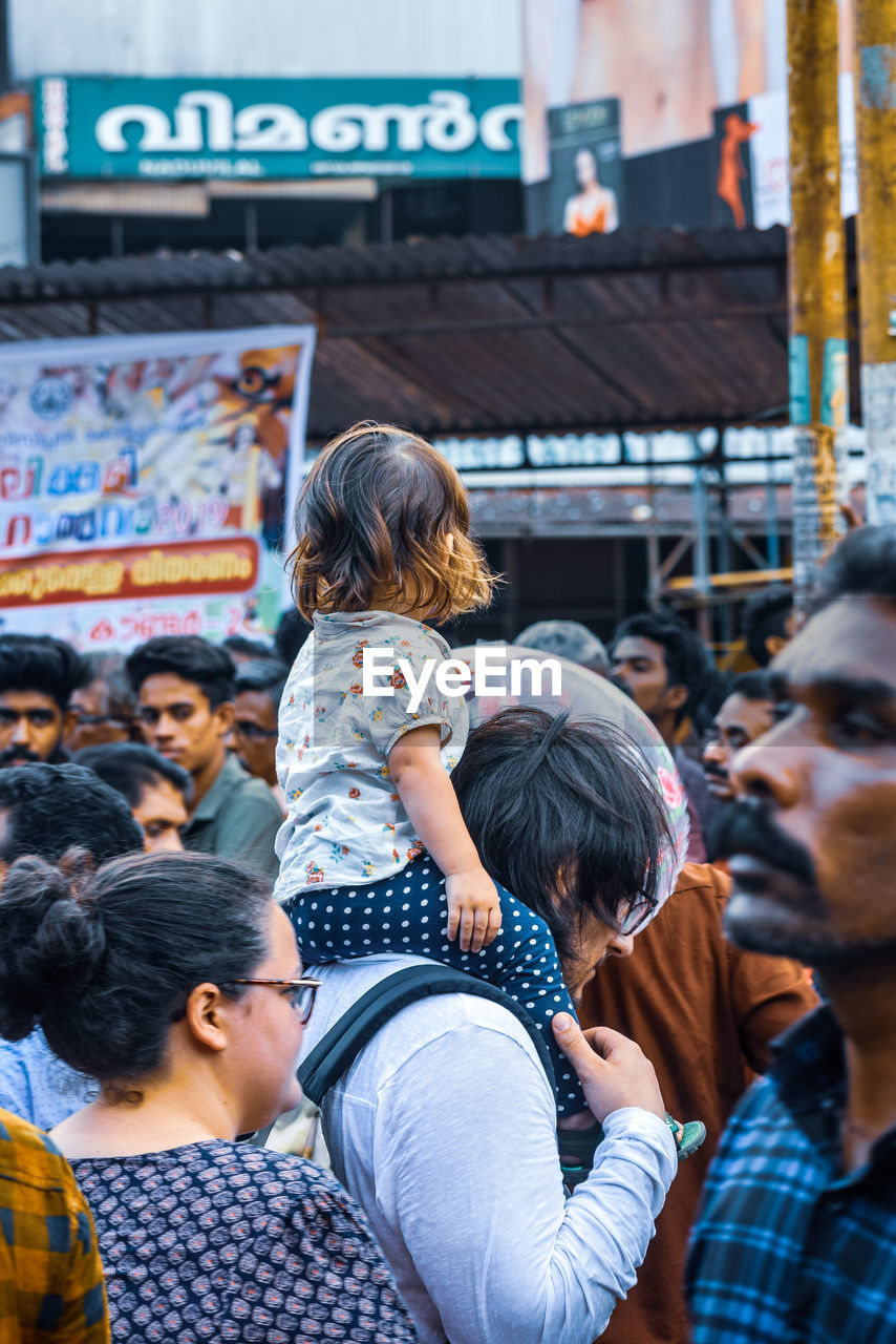 REAR VIEW OF PEOPLE STANDING IN FRONT OF BUILDING