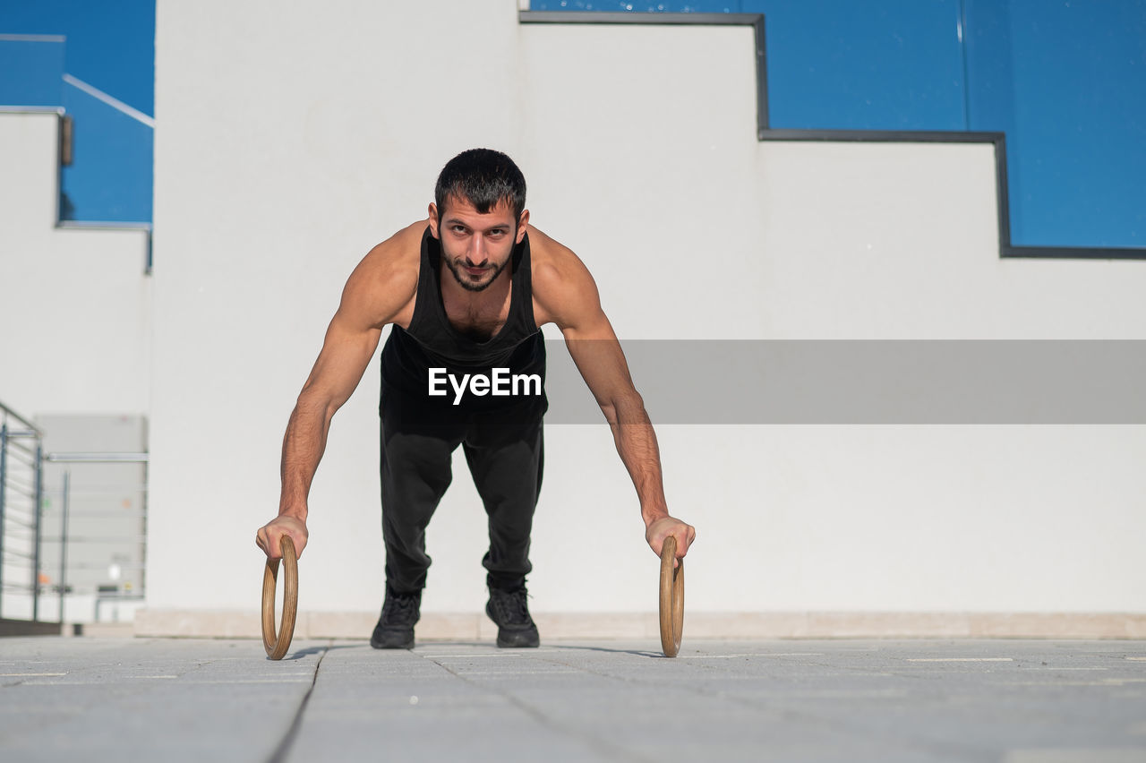 full length of young man exercising on floor