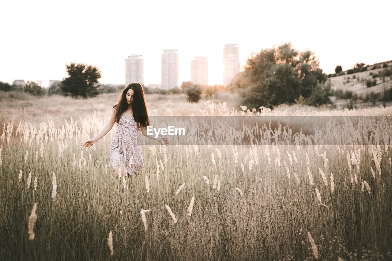 Young woman walking amidst plants on field