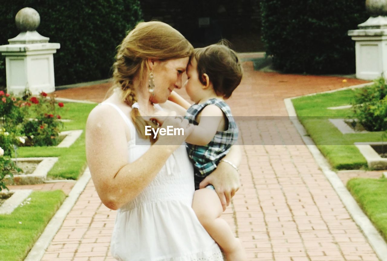 Mother looking at cute daughter while standing on footpath