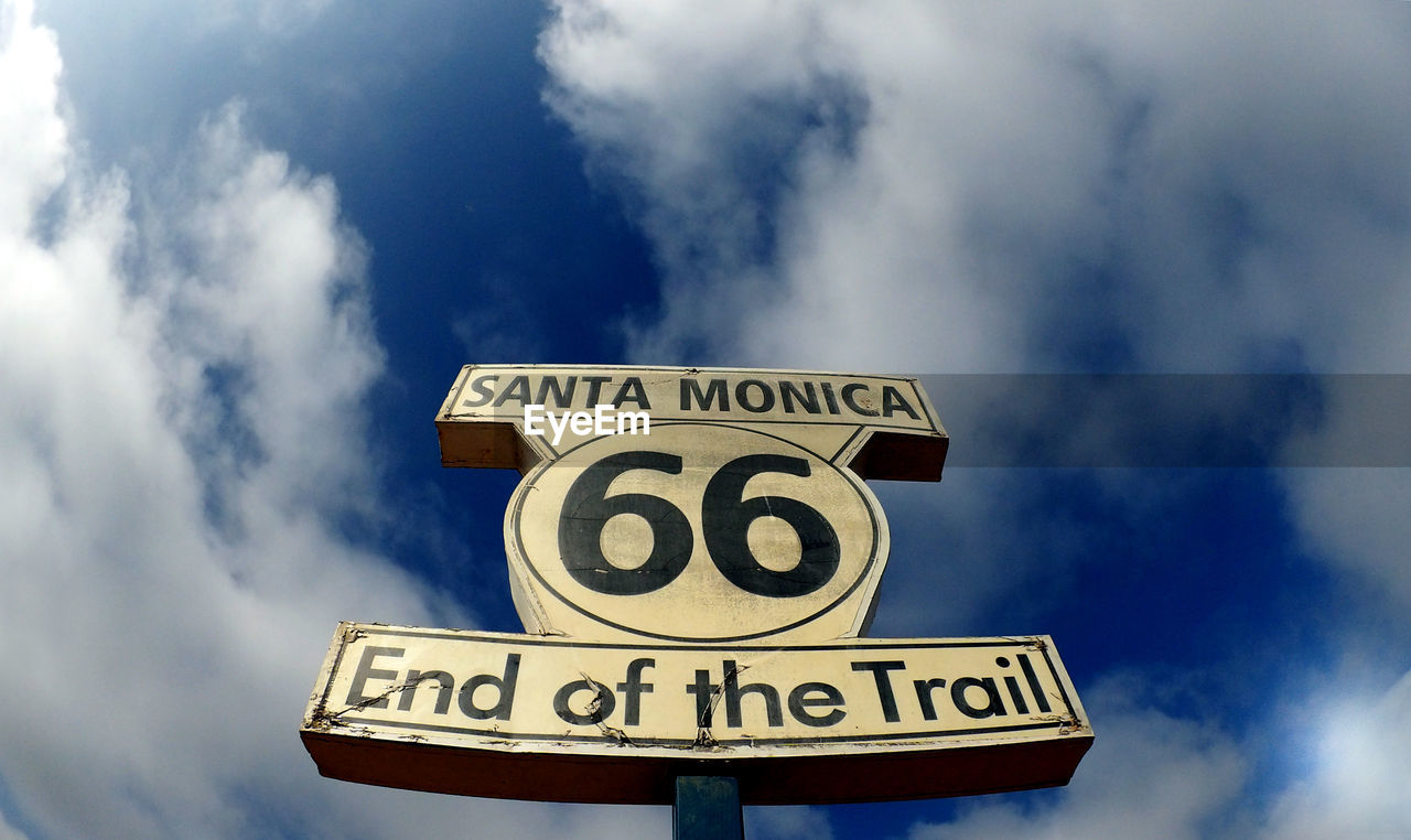 Low angle view of road sign against cloudy sky