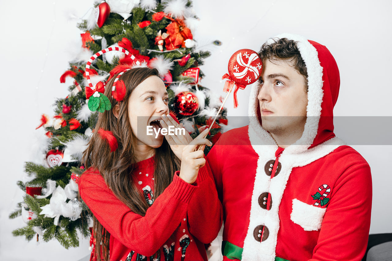 Smiling couple standing by christmas tree at home