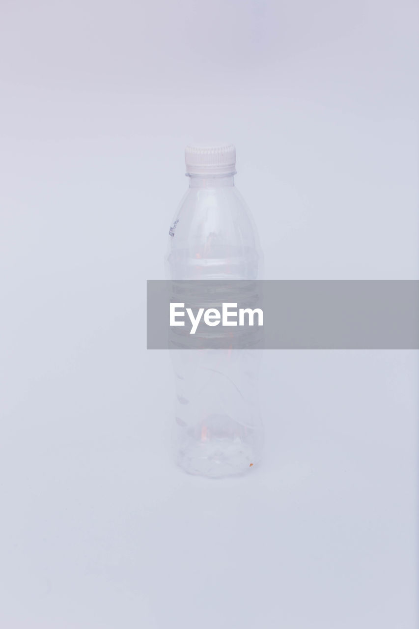 CLOSE-UP OF GLASS BOTTLE ON WHITE BACKGROUND