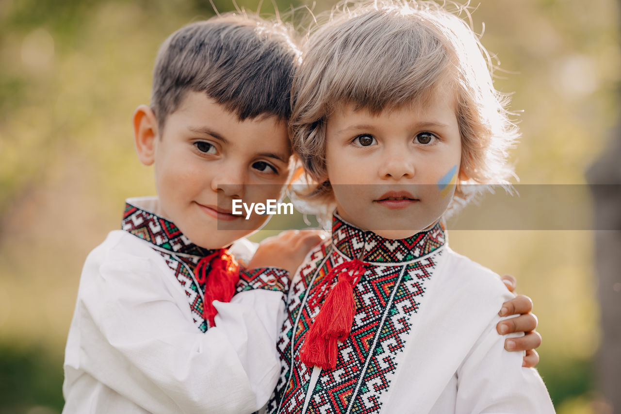 Boy embracing brother with ukraine flag on face