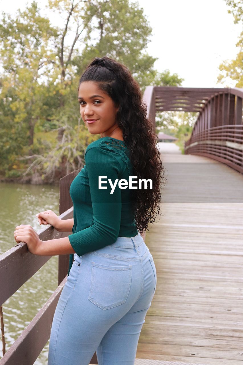 Portrait of young woman standing against lake