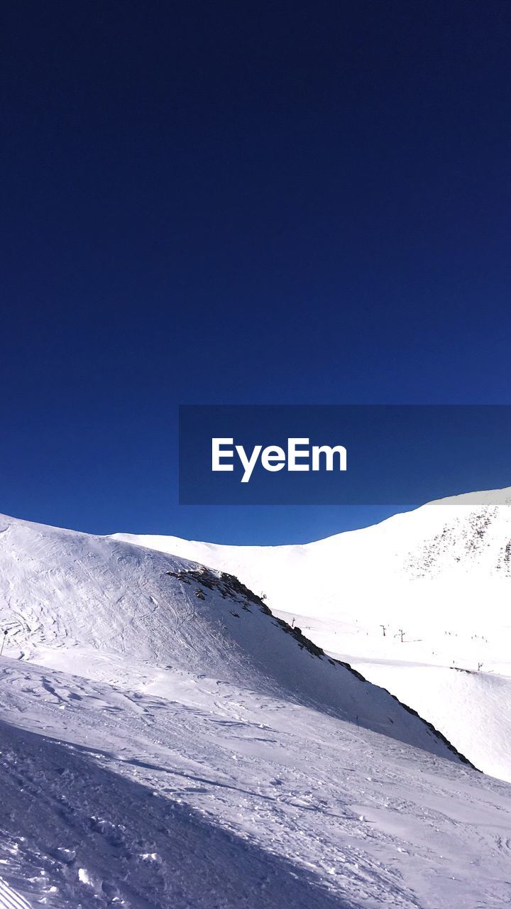 Scenic view of snowcapped mountains against clear blue sky