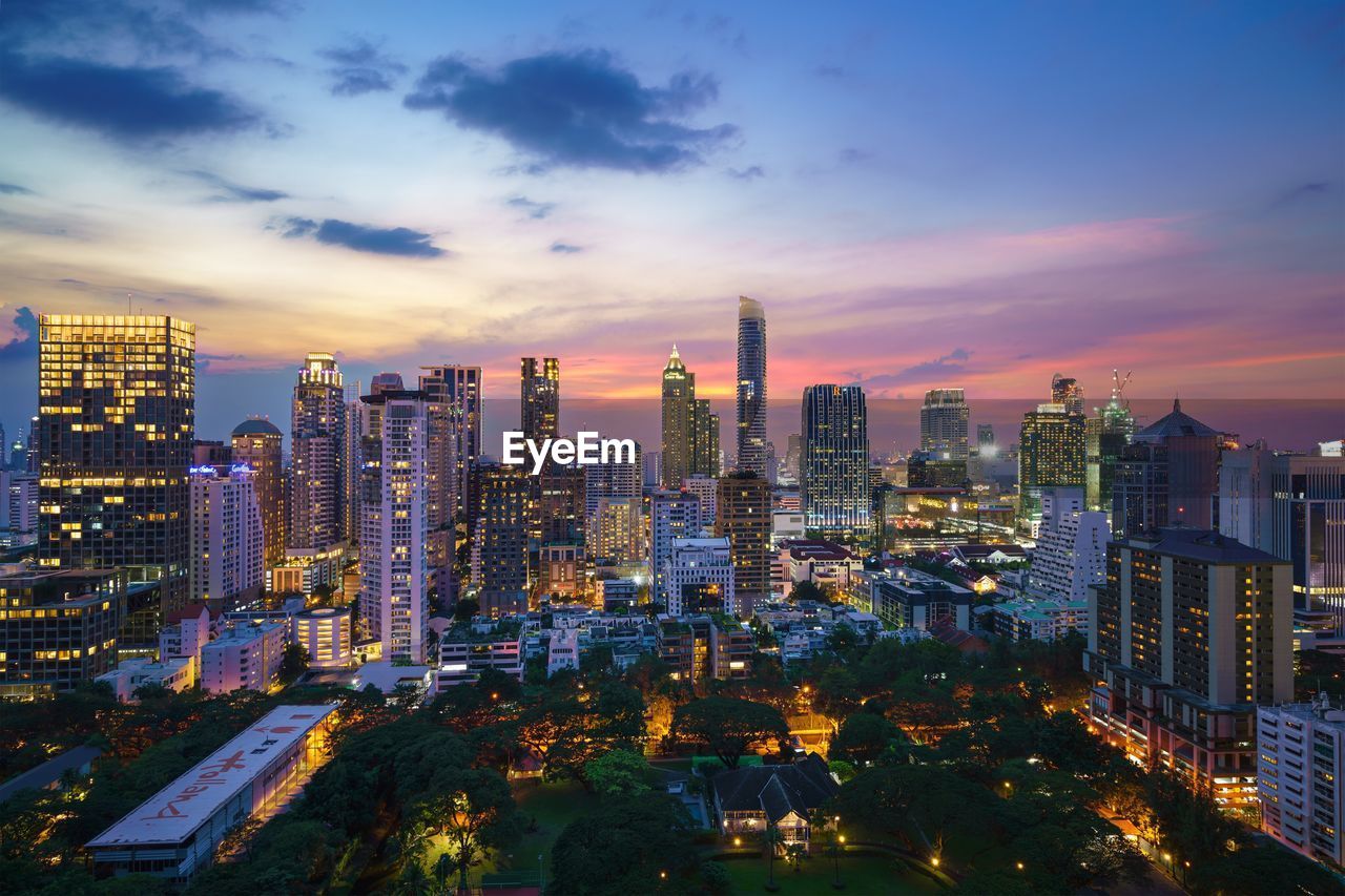 High angle view of illuminated skyscrapers against cloudy sky at dusk