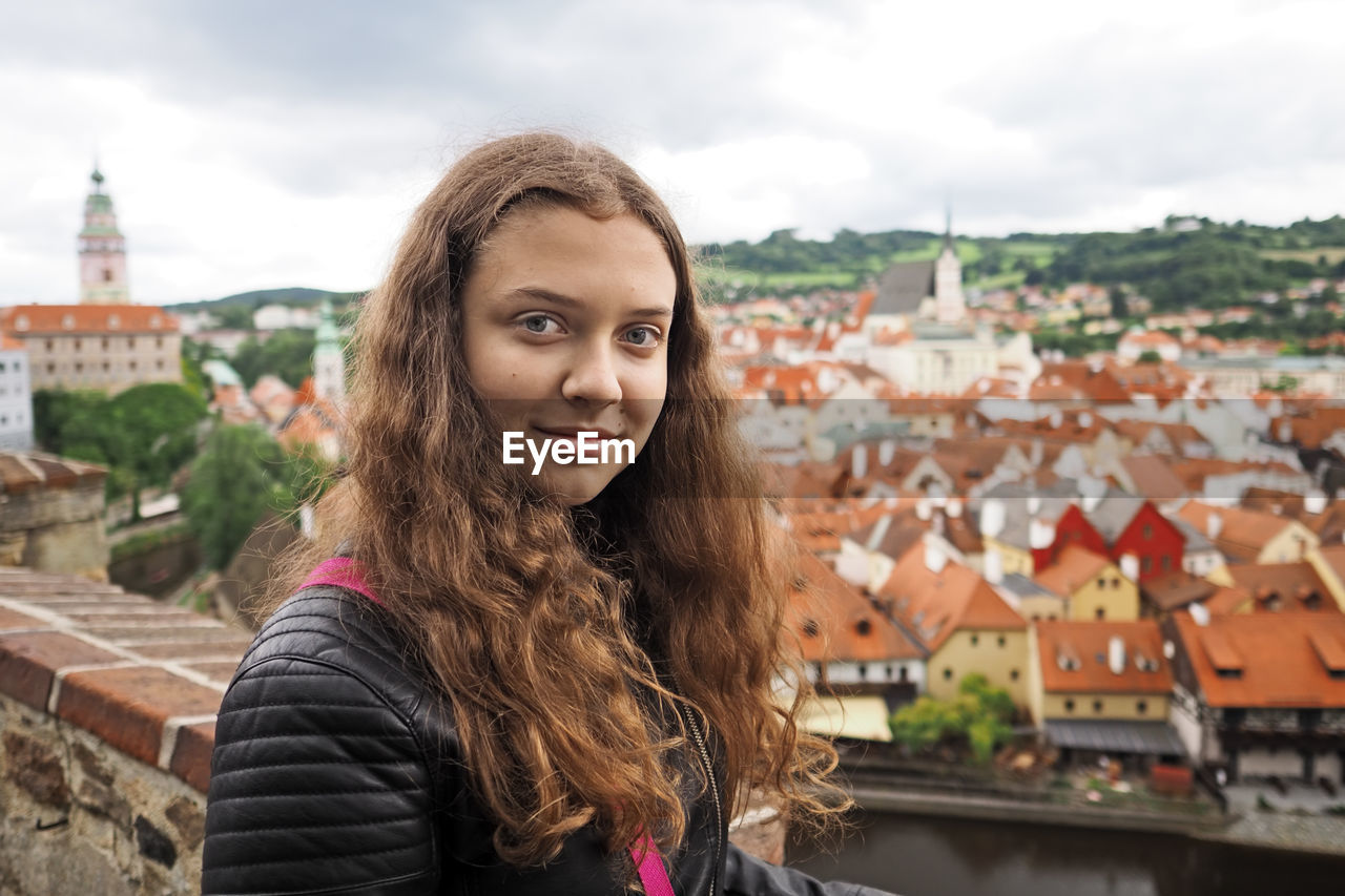 Young girl takes a selfie photo on the background of the historic town, city czech krumlov,