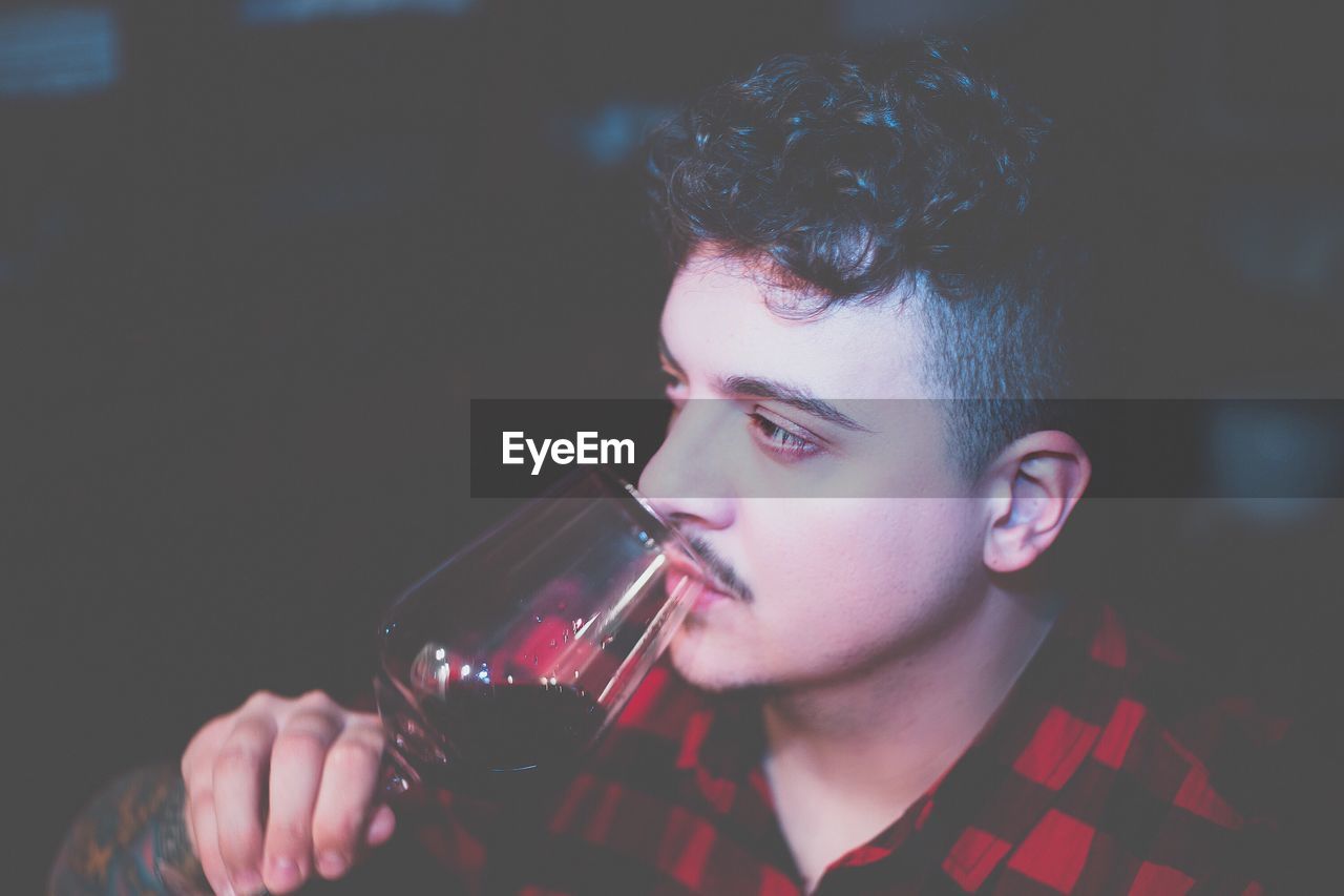 Close-up of man drinking red wine at night